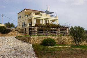 a house behind a stone wall and a stone path at House with amazing ocean view and patio - pool in Porto Heli