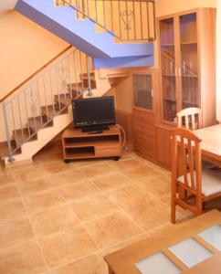 a living room with a tv on a table and a staircase at CASA RURAL HOCES DEL MESA in Jaraba