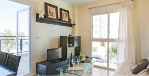 sala de estar con mesa de cristal y TV en Aguamarina Golf 3, en Oliva