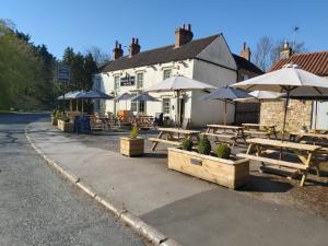 un grupo de mesas y sombrillas frente a un edificio en The Masons Arms, en Harrogate