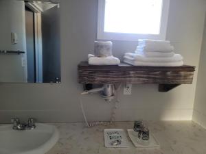 baño con lavabo y estante con toallas en Parkside Inn en Grande Prairie