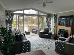 sala de estar con sofá, sillas y chimenea en Beautiful and Tranquil Lakeside Lodge - Sleeps 5 en Northampton