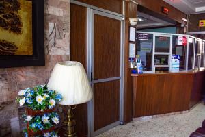 a lamp in a lobby next to a counter with flowers at Hotel Guadalajara in San Luis Potosí