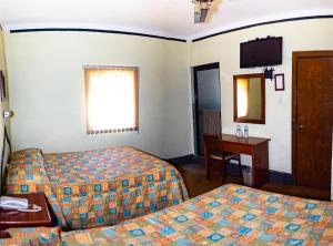Habitación de hotel con 2 camas, mesa y espejo en Hotel Guadalajara, en San Luis Potosí