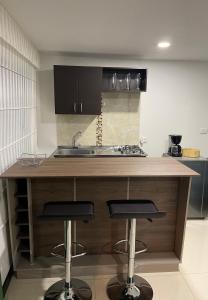 a kitchen with a sink and two bar stools at Apartaestudio Guatavita in Guatavita