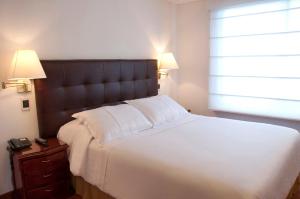 a bedroom with a large white bed and a window at Apartaestudios Los Andes in Bogotá +60 photos