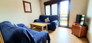 ein Wohnzimmer mit einem blauen Sofa und einem TV in der Unterkunft Piso El PUNTUAL de arriondas in Les Arriondes