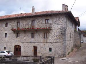 a stone building with a car parked in front of it at Casa Rural Barbonea in Lekunberri