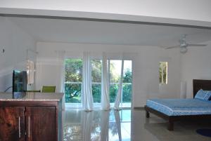 a living room with a bed and a large window at Vue Apartment Hotel in Cap-Haïtien