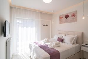 a white bedroom with a large bed with towels on it at Lux Palace Trikala in Tríkala