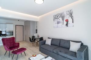 a living room with a gray couch and red chairs at Lux Palace Trikala in Tríkala