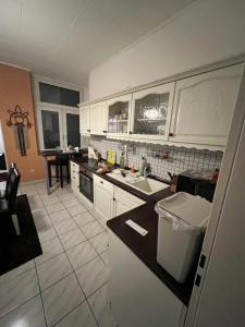 eine Küche mit weißen Schränken und einer schwarzen Arbeitsplatte in der Unterkunft Apartment BOZ Solingen in Solingen