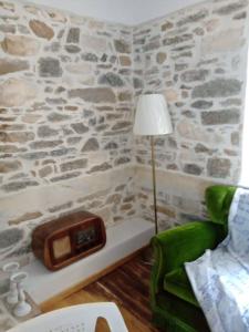 a room with a stone wall with a clock and a lamp at La Casa del Sol in Keramídhion