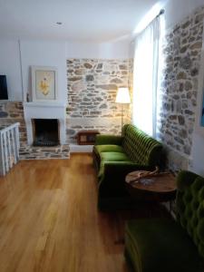 a living room with a green couch and a stone wall at La Casa del Sol in Keramídhion