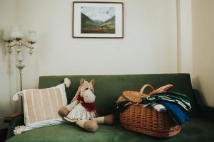 a stuffed horse sitting on a green couch with a basket at Guest House Lorem in Daugavpils