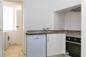 een witte keuken met een wastafel en een vaatwasser bij Estrela Garden Apartment in Lissabon