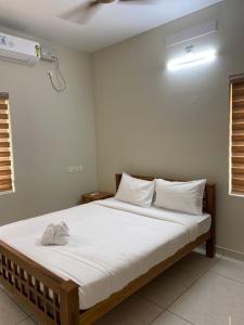 - une chambre dotée d'un grand lit avec des draps et des oreillers blancs dans l'établissement Nimet Residency, à Ernakulam