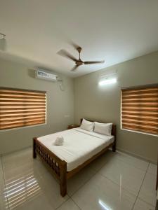- une chambre avec un lit et un ventilateur de plafond dans l'établissement Nimet Residency, à Ernakulam