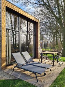 a couple of chairs and a table on a deck at Nieuw! Sfeervol Tiny House in de natuur en aan het water in Hulshorst