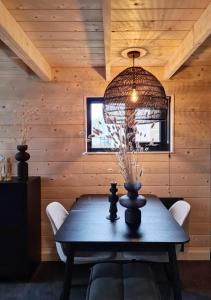 a dining room with a table and a chandelier at Nieuw! Sfeervol Tiny House in de natuur en aan het water in Hulshorst