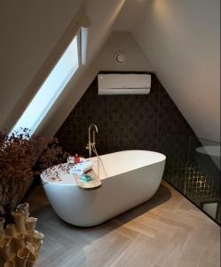 a bathroom with a bath tub in the attic at Harbour Suites Boutique Hotel in Monnickendam