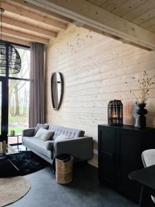 un soggiorno con divano e parete in legno di Nieuw! Sfeervol Tiny House in de natuur en aan het water a Hulshorst