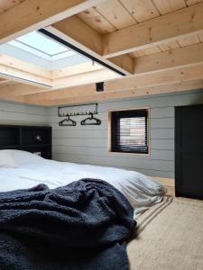 um quarto com uma cama grande num tecto de madeira em Nieuw! Sfeervol Tiny House in de natuur en aan het water em Hulshorst