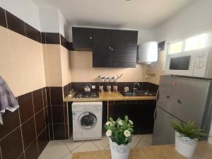a small kitchen with a washing machine and a sink at NRY Home magnifique Appartement , prêt de plage in Martil
