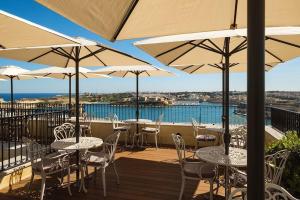 a deck with tables and chairs and umbrellas at The Gomerino Hotel in Valletta