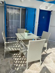 een patio met een tafel en stoelen en een blauwe deur bij Mediterranean sunset in Klorakas