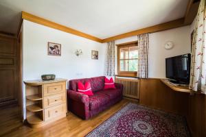 sala de estar con sofá rojo y TV en Chalet Aldian, en Selva di Val Gardena