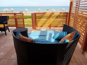 einen Stuhl mit Kissen auf einer Terrasse mit Strand in der Unterkunft Breathtaking Luxury & Spacious 2-Bedroom 1st Row Direct Seaview at Stella Sea View Sokhna in Ain Suchna
