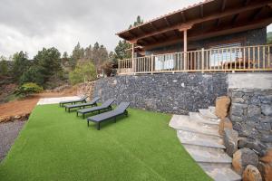 a row of benches sitting on a lawn in front of a house at Finca Ecológica Ferrera. Alojamiento Rural. in Arafo