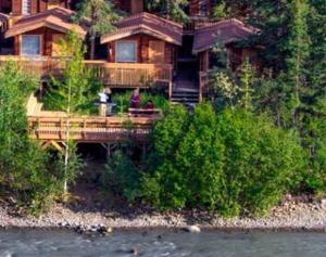 a large wooden house on the side of a river at Denali Park Village in McKinley Park