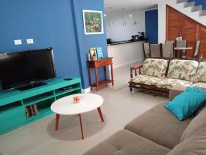 uma sala de estar com um sofá, uma televisão e uma mesa em Casa Bela Paraty em Paraty