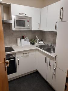 a kitchen with white cabinets and a sink and a microwave at Ferienwohnung Lucky Luggi in Bad Griesbach in Bad Griesbach