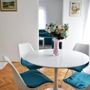 une table et des chaises blanches avec un vase de fleurs dans l'établissement Apartman Sanja, à Banja Luka
