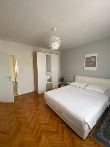 - une chambre avec un grand lit blanc et du parquet dans l'établissement Apartman Sanja, à Banja Luka