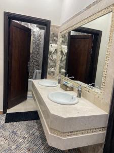a bathroom with two sinks and a large mirror at شقق سما العلا in AlUla