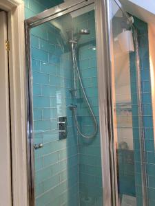 a blue tiled bathroom with a shower with at Bentley Rise in Lyme Regis