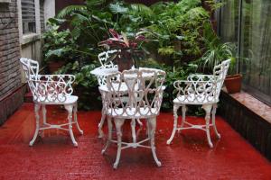 3 weiße Stühle und ein Tisch auf der Terrasse in der Unterkunft Hotel Yaro in Gualeguaychú