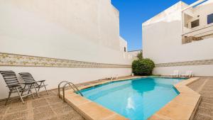a swimming pool in a courtyard with chairs and a building at Villa Dani in Pollença