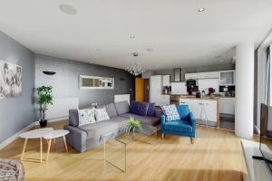 a living room with a couch and chairs and a kitchen at Deluxe three bedroom Apartment by London ExCeL Stays in London