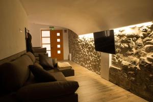 Una sala de estar con un sofá y una pared de piedra. en Casa rural Can Miralter, en Camprodon