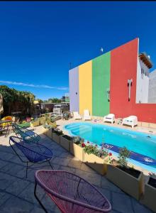 a swimming pool with chairs and a colorful wall at Villa Color in Las Grutas