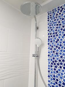 y baño con ducha y azulejos azules y blancos. en La Minoterie - Studio avec kitchenette et Chambre d'hôtes, en Le Palais