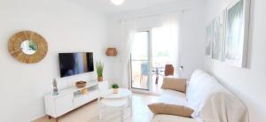 een witte woonkamer met een witte bank en een tv bij Apartamento El Sueño II in Denia