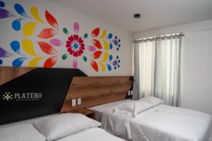 a bedroom with two beds and a painting on the wall at Platero Hotel in Ayacucho