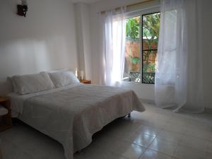 a white bedroom with a bed and a window at Pequeño Paraíso un lugar ventilado y acogedor in El Placer