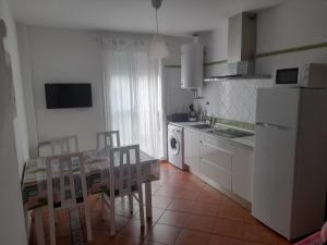 a kitchen with a table and a white refrigerator at El Sardinero in Chipiona